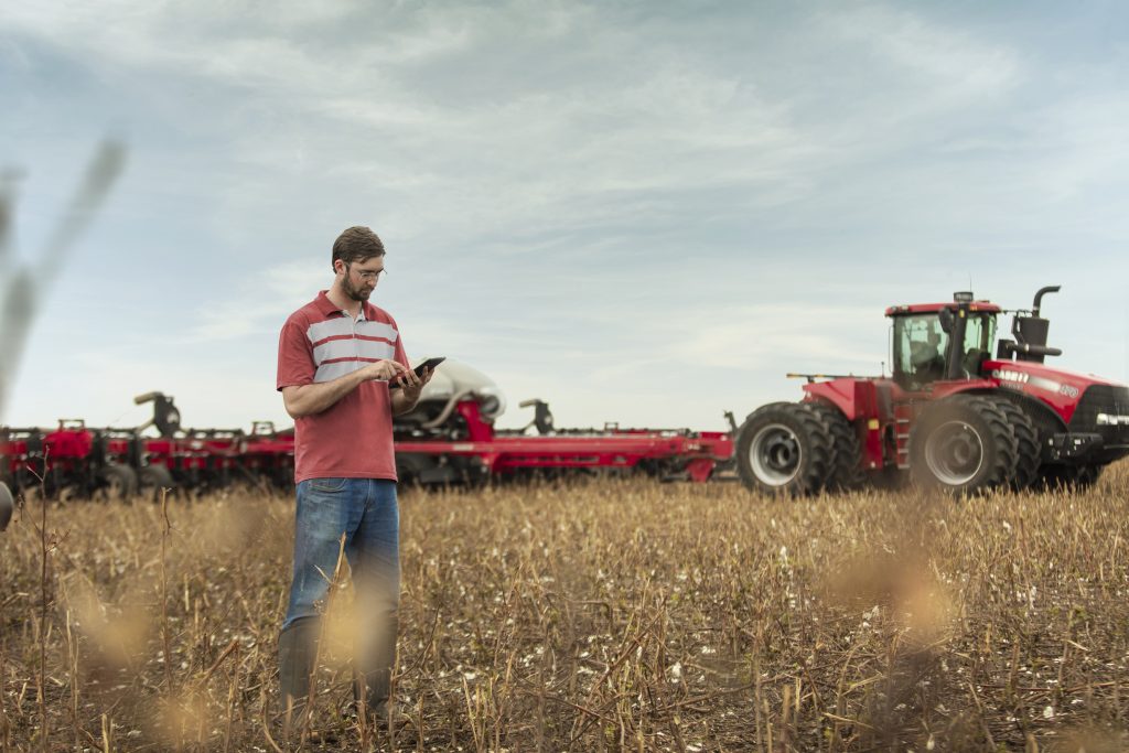 homem com tablet no campo e trator